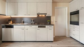 Une cuisine moderne avec des meubles de couleur bois clair, un four encastré et un lave-vaisselle.