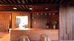 A wooden reception desk with a tiled floor, a potted plant, and a wooden bench.