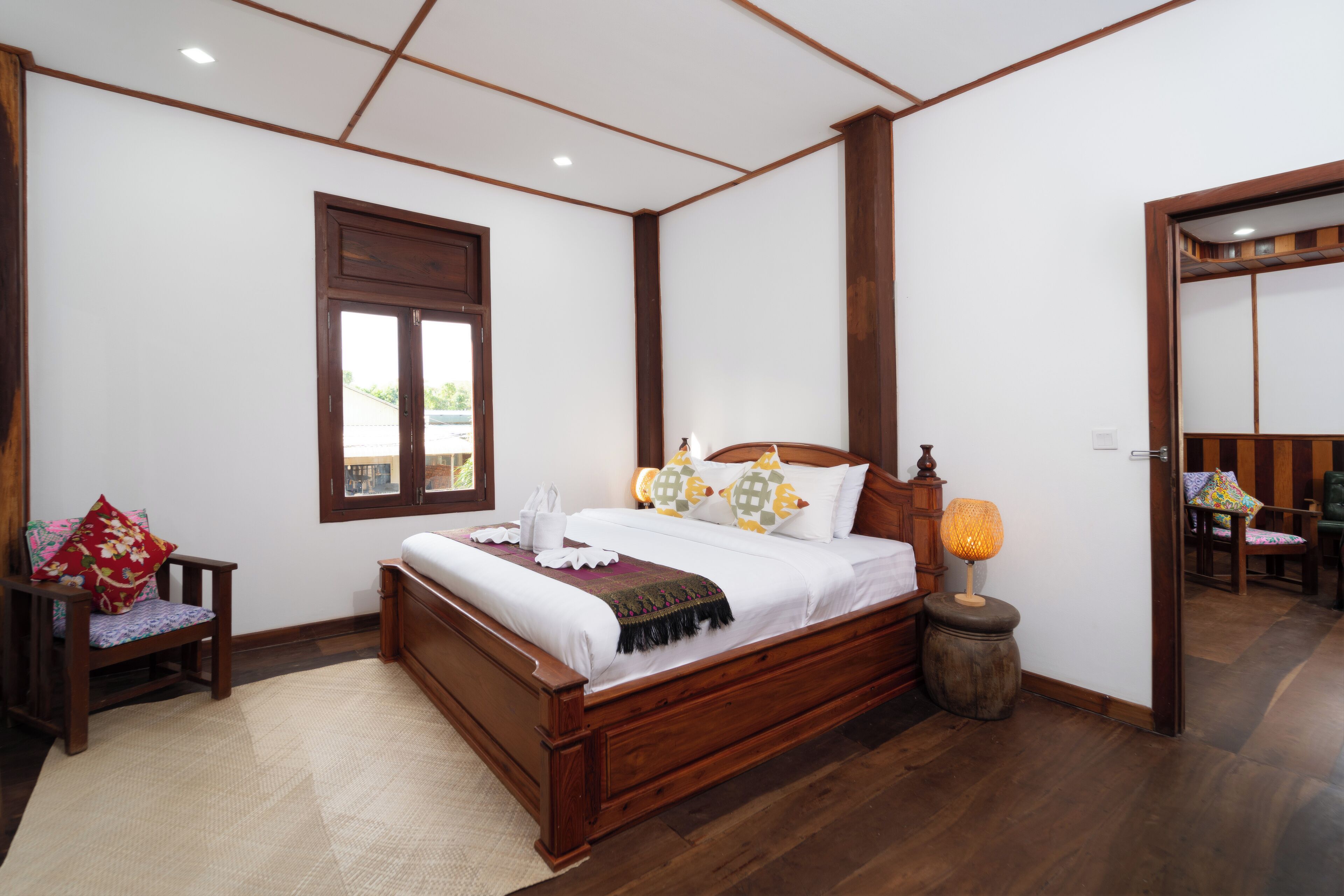 Een slaapkamer met een houten bed, een nachtkastje met een lamp, een stoel en een raam.