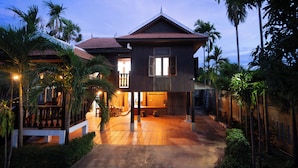A two-story house with a tiled patio, a balcony, and a wooden fence.