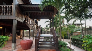 A wooden staircase leading to a covered area with a bench and a large planter.