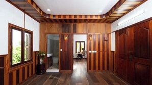 A hallway with wooden paneling, a potted plant, and a person working at a desk.