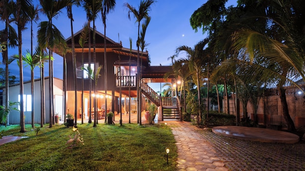 A modern house with a spacious patio, a staircase, and a well-maintained lawn.