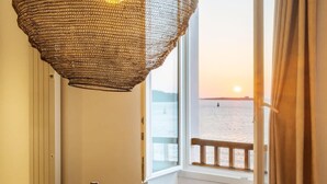 A table set for dining with a bottle of wine, glasses, and plates, overlooking a body of water at sunset. - Beautiful Seaview Flat in Stagadon Island (Landeda)