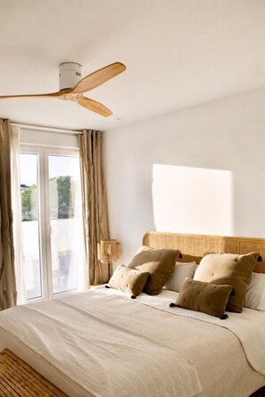A bedroom with a bed, a ceiling fan, a window with curtains, and a view of greenery outside. - Luxury Mediterranean Villa in Roche, Conil, Cádiz. (Roche)