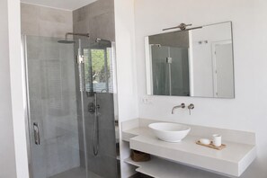 A modern bathroom with a glass-enclosed shower, a white sink with a vessel basin, and a large mirror above the vanity. - Luxury Mediterranean Villa in Roche, Conil, Cádiz. (Roche)