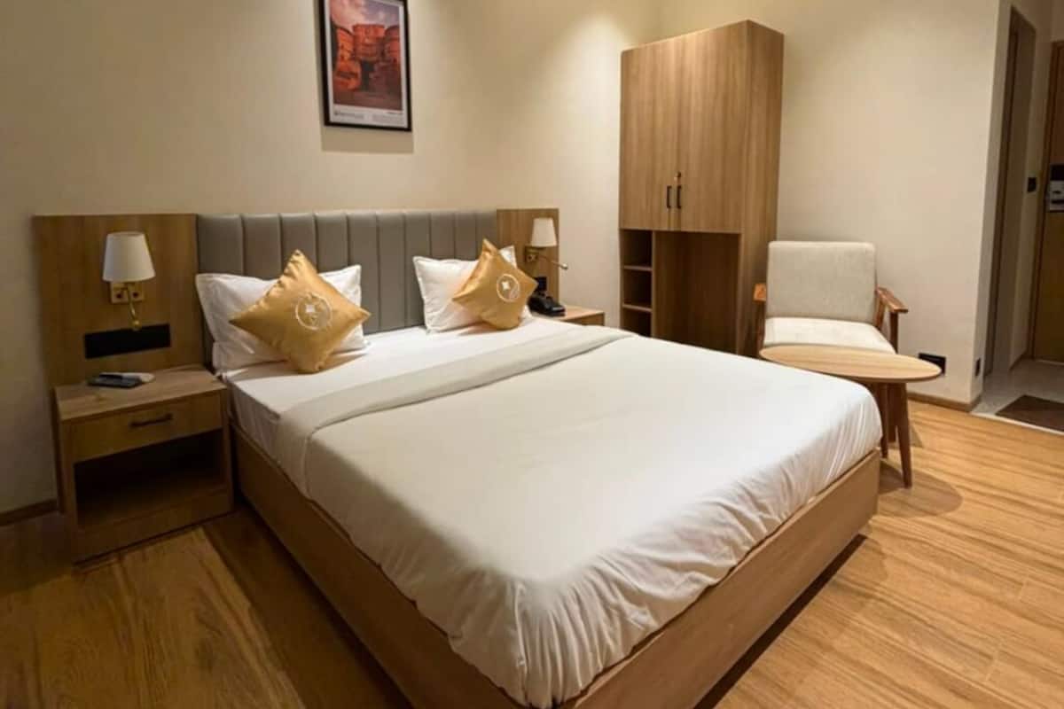 Una habitación de hotel con una cama grande, mesitas de noche, un armario y una silla.