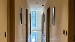 A long, narrow hallway with wooden doors and framed pictures on the walls. - The Shivanta Inn (Gandhinagar)