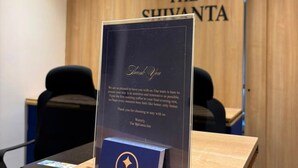 A reception desk with a thank you card, a wooden wall with the hotel name, and two black office chairs. - The Shivanta Inn (Gandhinagar)