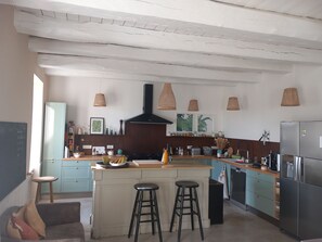 A modern kitchen with a central island, bar stools, a built-in oven, and pendant lights. - House in the heart of the village with a pool, near La Rochelle and Île de Ré (Vérines)