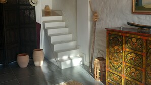 A staircase leading to a second floor, a woven rug, a cabinet with floral designs, and a hanging plant. - House in the heart of the village with a pool, near La Rochelle and Île de Ré (Vérines)