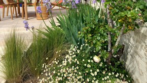 A patio with outdoor furniture, a large umbrella, and a variety of plants including roses and daisies. - House in the heart of the village with a pool, near La Rochelle and Île de Ré (Vérines)