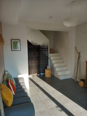 A modern interior with a staircase, a sofa with colorful cushions, and a decorative wall piece. - House in the heart of the village with a pool, near La Rochelle and Île de Ré (Vérines)