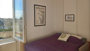 A bedroom with a bed, a window, and two framed pictures on the wall. - House in the heart of the village with a pool, near La Rochelle and Île de Ré (Vérines)