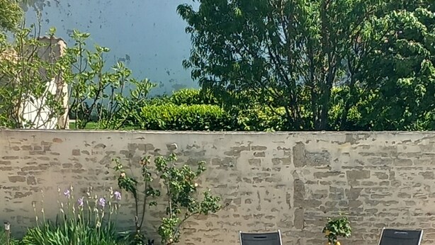 A swimming pool with two lounge chairs and a small table, surrounded by a stone wall and greenery. - House in the heart of the village with a pool, near La Rochelle and Île de Ré (Vérines)