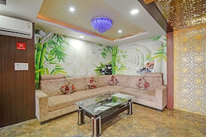 A reception area with a sofa, a glass coffee table, and a decorative ceiling. - Townhouse Oak Iskcon Jaipur Formerly Olive Greens (Jaipur)