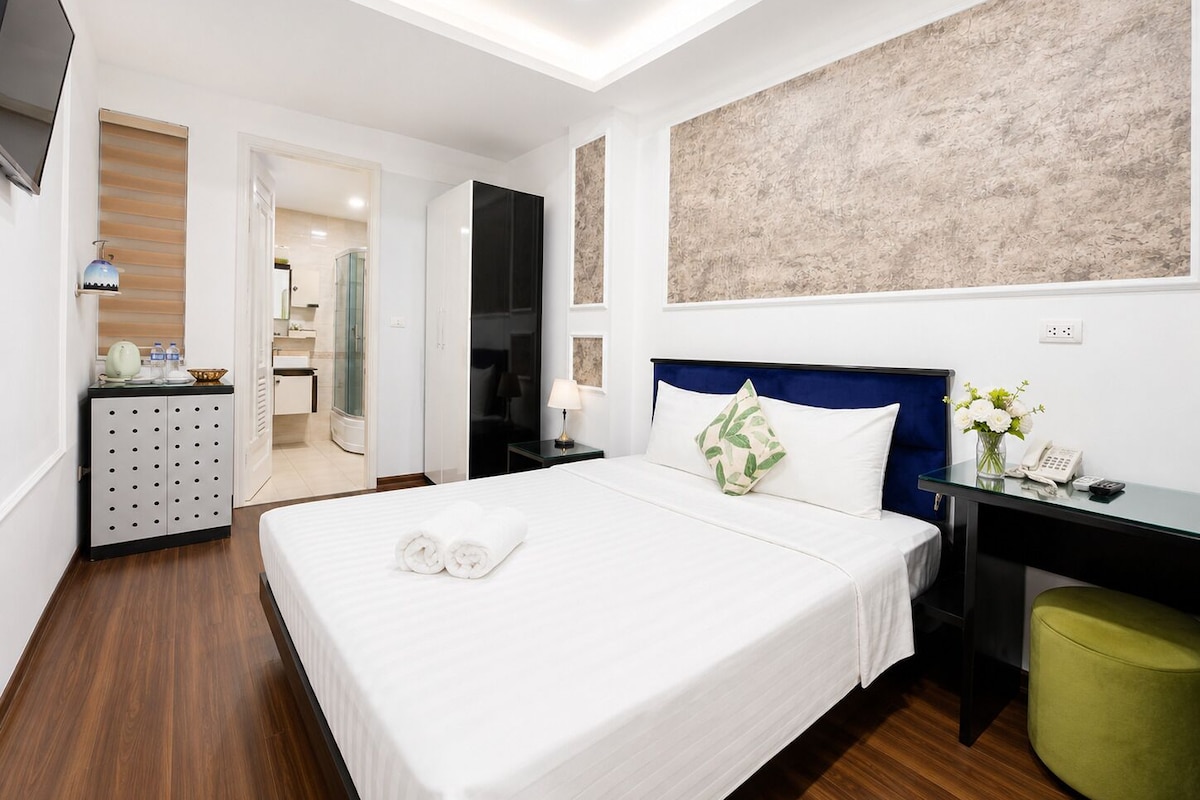 A hotel room with a bed, a desk, a telephone, and a mirror.