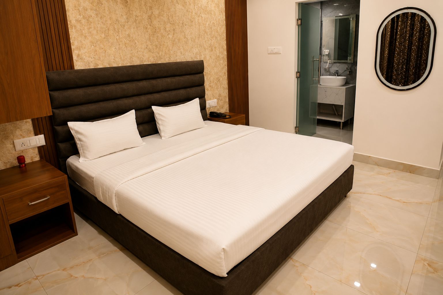 Una habitación de hotel moderna con una cama grande, una mesita de noche y un baño visible a través de una puerta abierta.