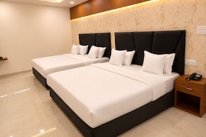 Habitación de hotel con dos camas, una mesita de noche de madera con un teléfono y una pared con diseño de mármol.