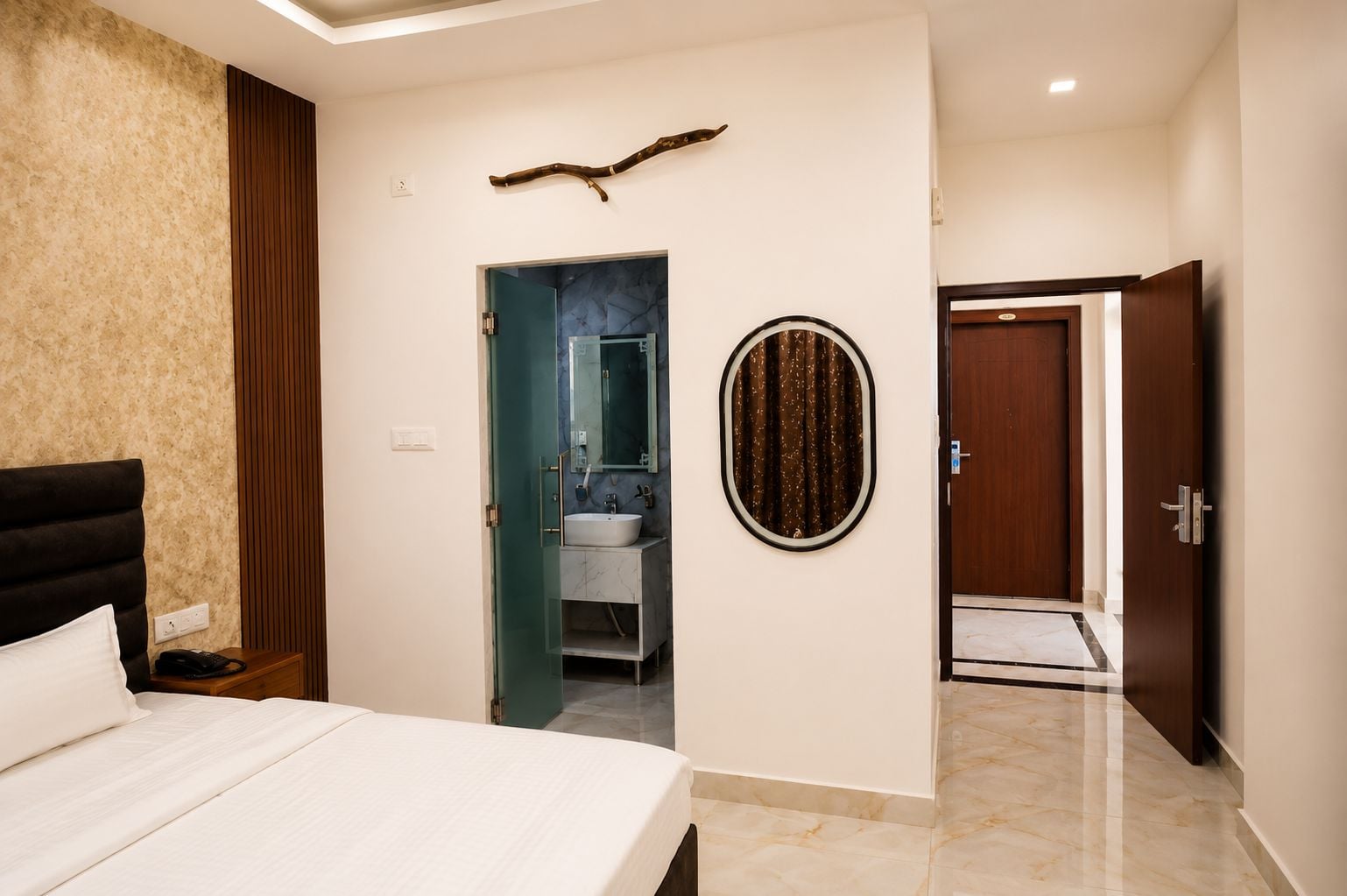 Un dormitorio con cama, un baño con lavabo y espejo, y una puerta que da a otra habitación.