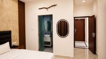 Un dormitorio con cama, un baño con lavabo y espejo, y una puerta que da a otra habitación.
