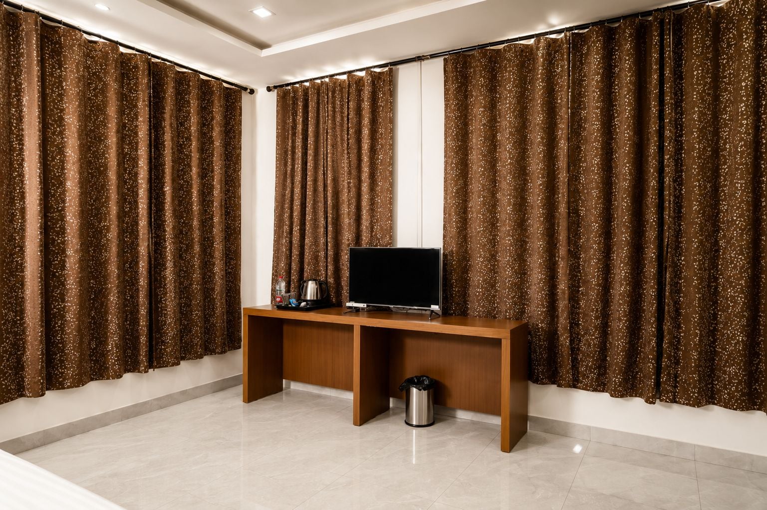 Una habitación con un escritorio de madera, un televisor y cortinas.