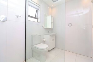 A modern bathroom with a toilet, sink, and mirror. - Modern Studio Apartment in Sandton (Johannesburg)