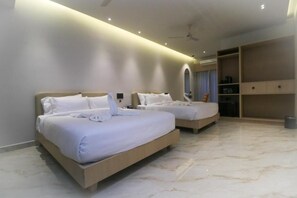 Habitación de hotel con dos camas, ventilador de techo, minibar y un espejo grande.