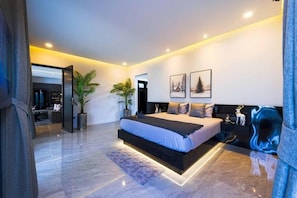 Ein modernes Schlafzimmer mit einem großen Bett, einem Nachttisch, einer Topfpflanze und einem an der Wand befestigten Kunstwerk.