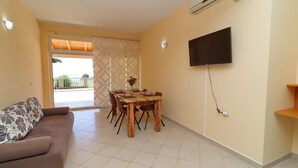 A living room with a sofa, a dining table with chairs, a TV mounted on the wall, and an air conditioning unit. - Apartments Villa Michele-one Bedroom Apartment With Terrace (Orebic)