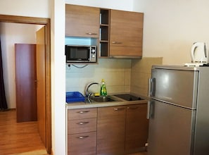 A compact kitchen with wooden cabinets, a microwave, a sink, and a refrigerator. - Beach House Zuljana - Two Bedroom Apartment With Terrace 2 (Ston)