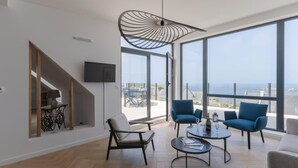 Ein modernes Wohnzimmer mit großem Fenster, Fernseher und einer Treppe.