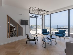 A modern living room with a large window, a TV, and a staircase. - Magnificent Seafront Duplex in Porspoder (Porspoder)