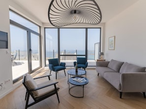 A modern living room with large windows, a ceiling light fixture, and a view of the sea. - Magnificent Seafront Duplex in Porspoder (Porspoder)