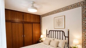 Un dormitorio con cama, mesitas de noche, ventilador de techo y armario.