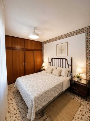 Ein Schlafzimmer mit Bett, Nachttischen, Deckenventilator und Kleiderschrank.