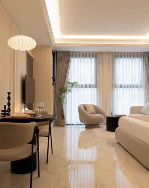 Ein modernes Wohnzimmer mit Sofa, Sessel, Esstisch und Fernseher.