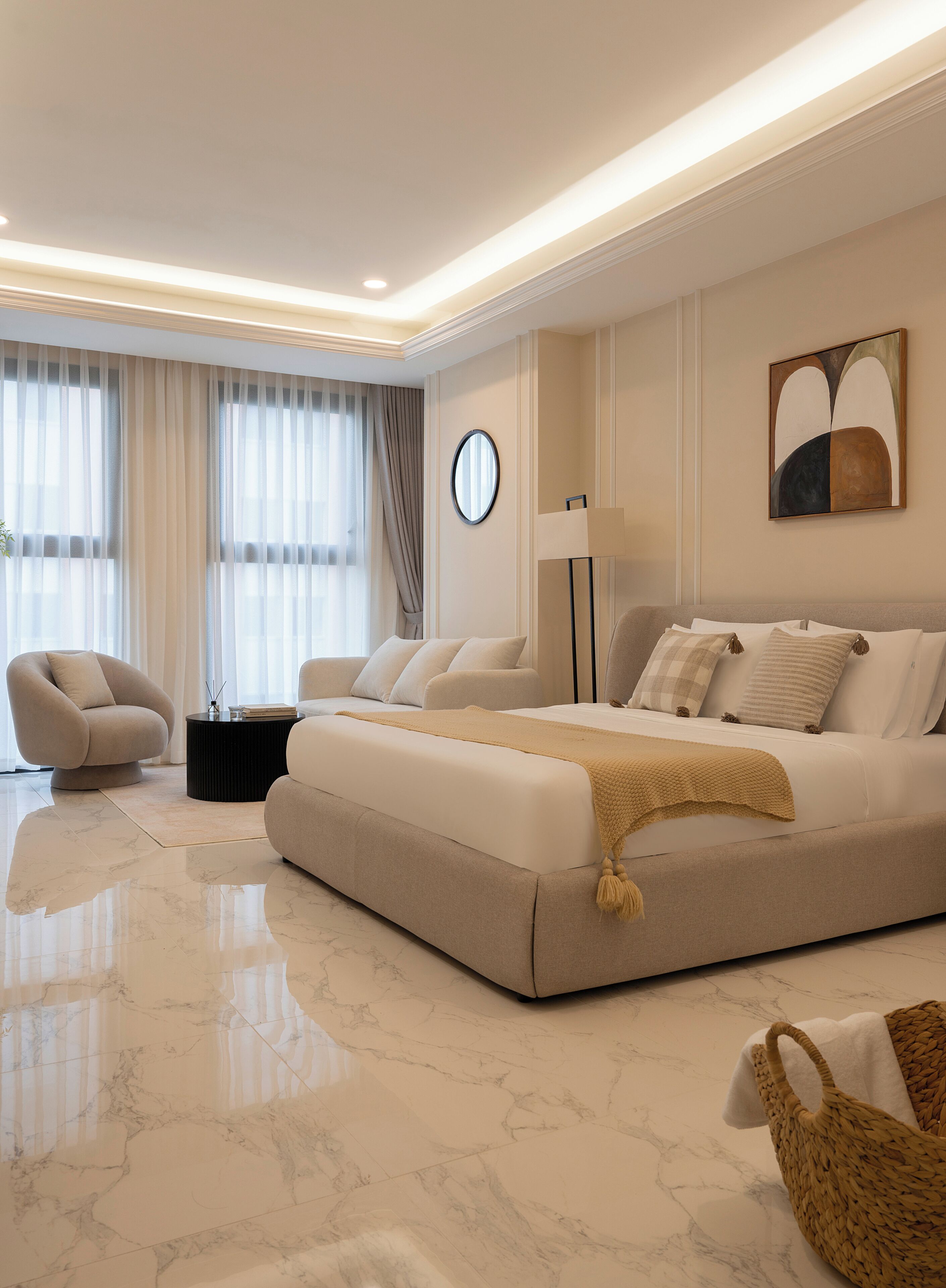 A modern bedroom with a large bed, a round mirror, a side table, and a chair.