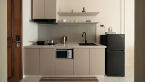 A modern kitchen with a built-in oven, a black refrigerator, and a stainless steel kettle. - Madison Grand Studio - King Bed - Pool & Gym access (Thành phố Hồ Chí Minh)