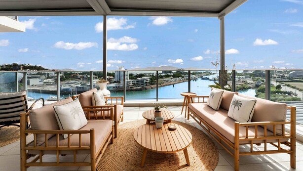 A balcony with a view of a marina, a round wooden table, and two sofas with cushions. - Absolute Waterfront Luxe Sub-Penthouse | 3BR | Panoramic Views (South Townsville)