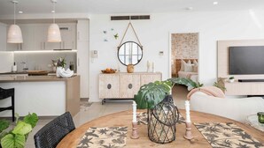 A modern kitchen with pendant lights, a dining area with a round table, and a living room with a TV. - Absolute Waterfront Luxe Sub-Penthouse | 3BR | Panoramic Views (South Townsville)