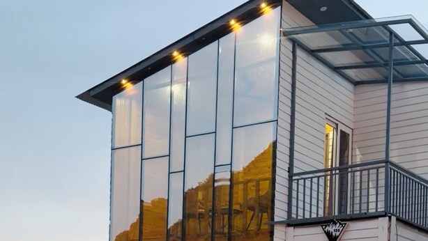 A modern building with large glass windows, a balcony, and a fire feature in the foreground. - The Kured Resort (Chakrata)