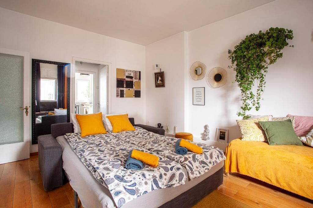 Un dormitorio con cama, mesitas de noche, un espejo y una planta colgante.