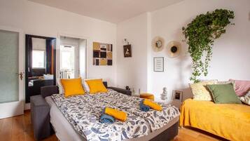 Un dormitorio con cama, mesitas de noche, un espejo y una planta colgante.