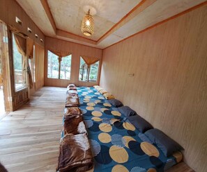 Ein Zimmer mit einem langen Bett, Holzwänden und großen Fenstern.