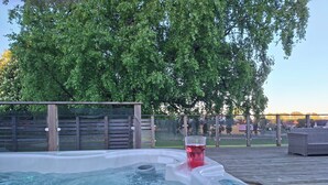 Een kuip met warm water, een houten terras en uitzicht op een woonwijk.