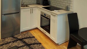 Een moderne keuken met witte kasten, een roestvrijstalen koelkast, een inbouwoven en een zwarte stoel.