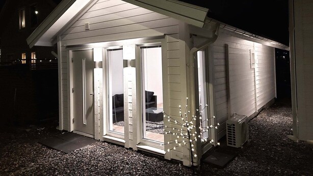 Een laag, klein gebouw met schuine kap en een veranda met glazen deuren.