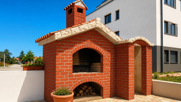 A brick-built outdoor fireplace with a chimney, a potted plant, and a stone-tiled patio. - 1 bedroom beautiful apartment in Sabunike (Sabunike)