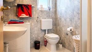 A bathroom with a toilet, sink, and a towel rack with a red towel. - 1 bedroom beautiful apartment in Sabunike (Sabunike)